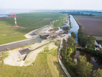 Luftbild: Im Vordergrund erstreckt sich die Baustelle der Hadelner Kanalschleuse - im Hintergrund ist die Elbe zu sehen.
